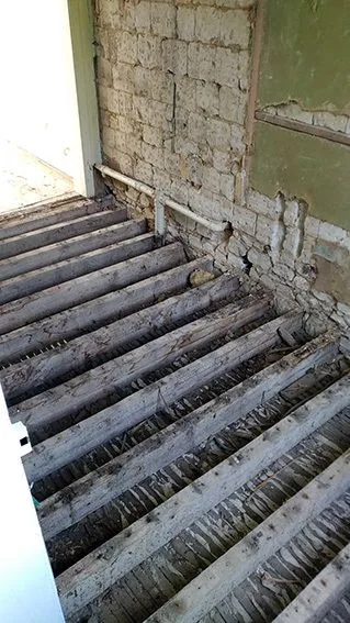 Mur décapé laissant apparaître briques et canalisations