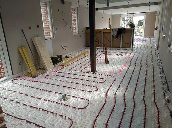 Pose d'un plancher chauffant et des réseaux dans une pièce en gros œuvre